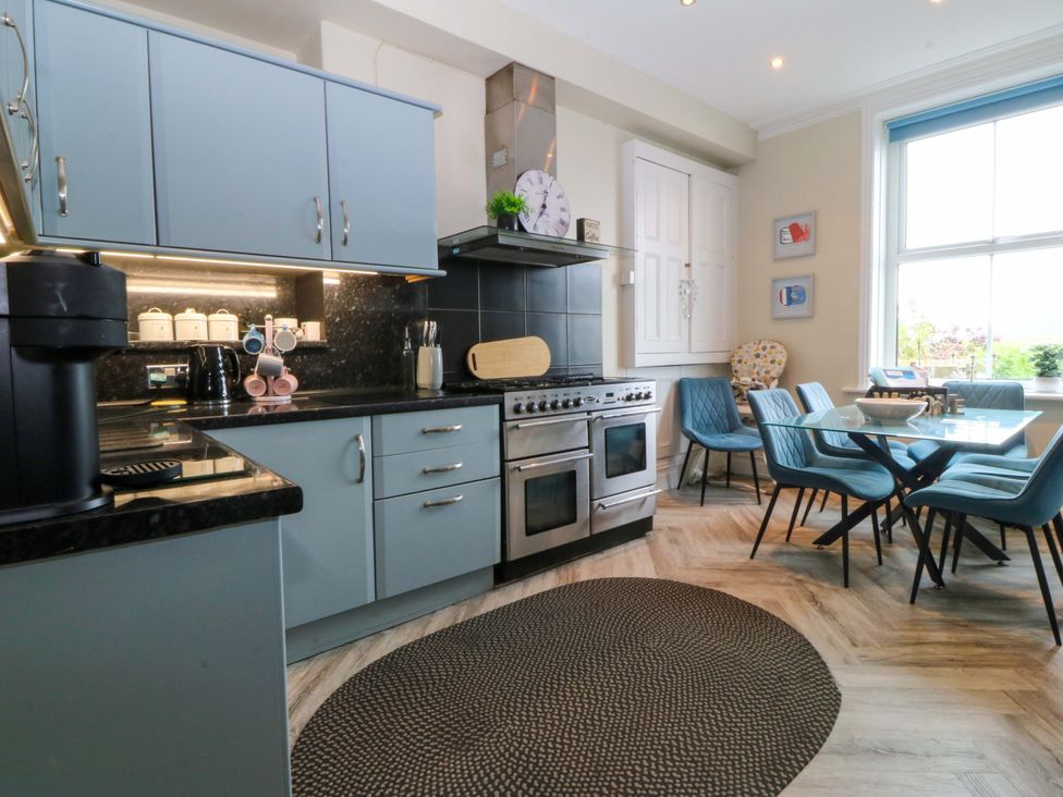 A kitchen with cabinets, stove, and dining area at Jack's House in Tywyn