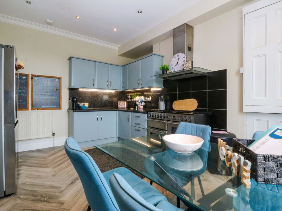 A kitchen with cabinets, stove, and dining table at Jack's House in Tywyn