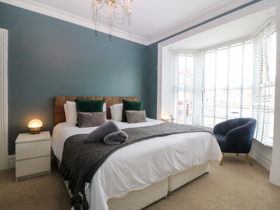 A bedroom with a bed and armchair at Jack's House in Tywyn