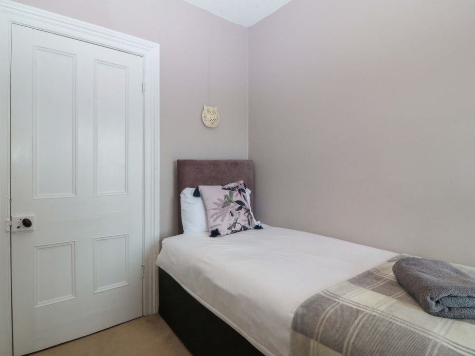 A bedroom with a single bed and door at Jack's House Tywyn