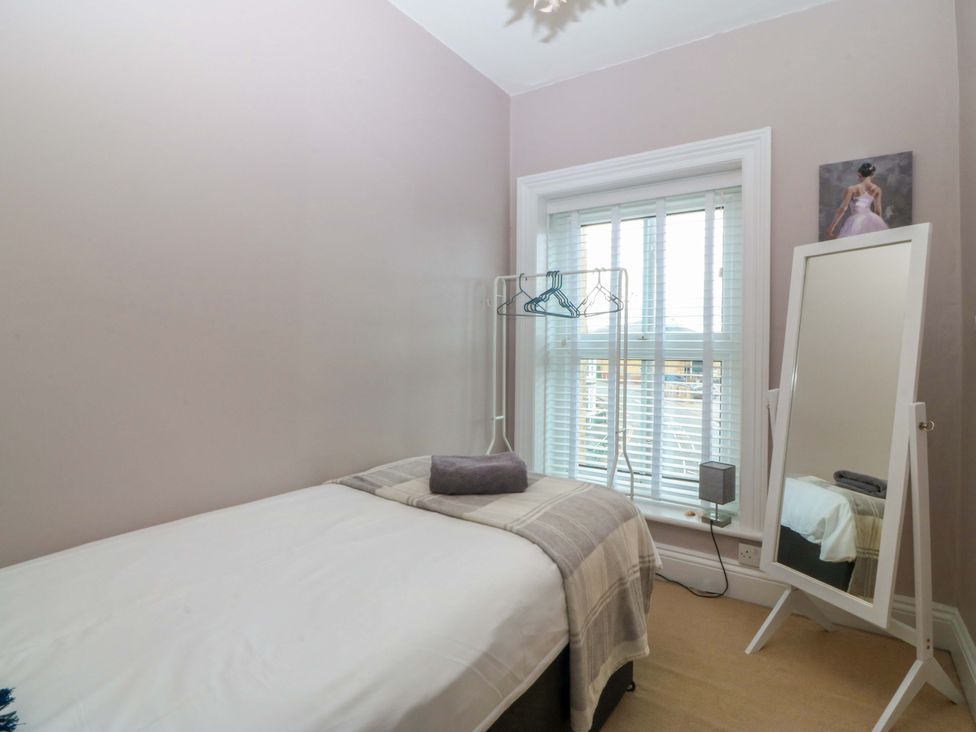 A bedroom with a bed and mirror at Jack's House in Tywyn