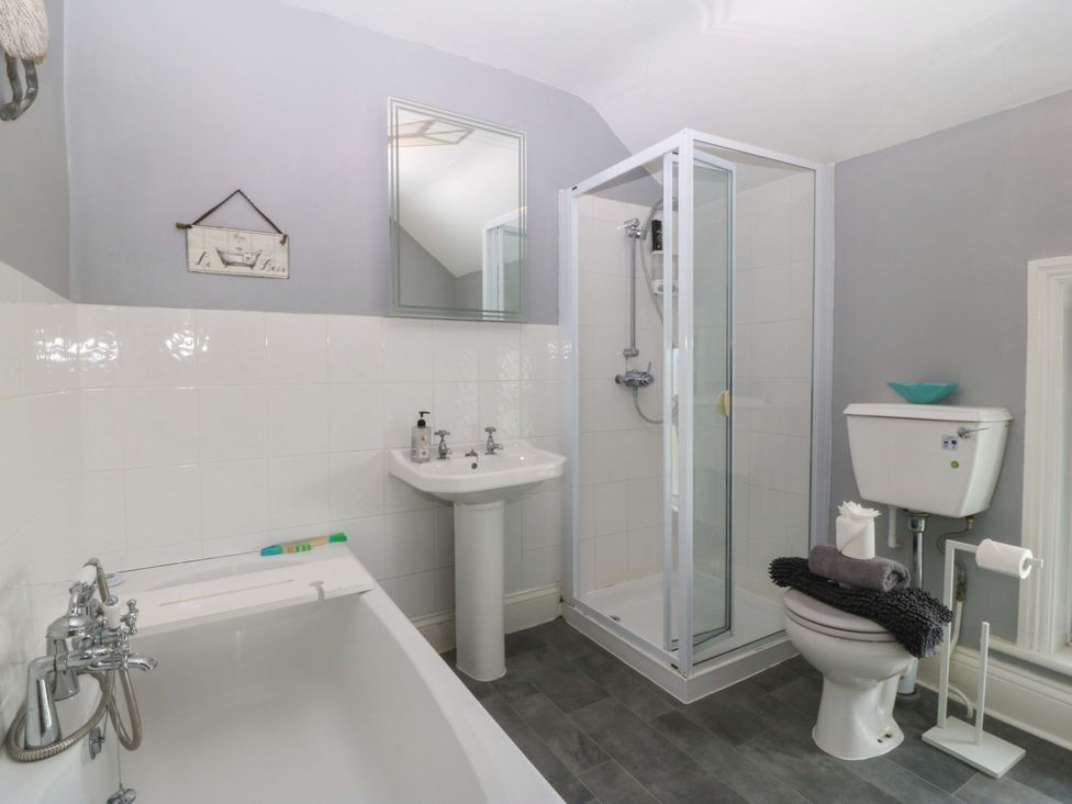 A bathroom with a shower, bathtub, sink, and toilet at Jack's House in Tywyn
