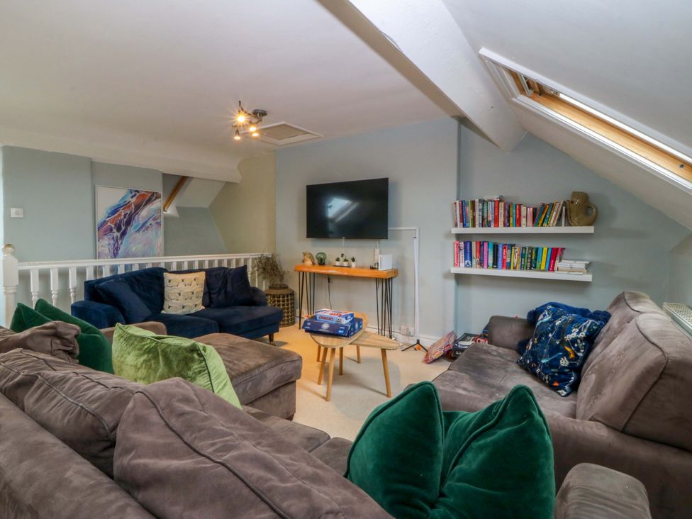 A living room with a television and bookshelves at Jack's House in Tywyn