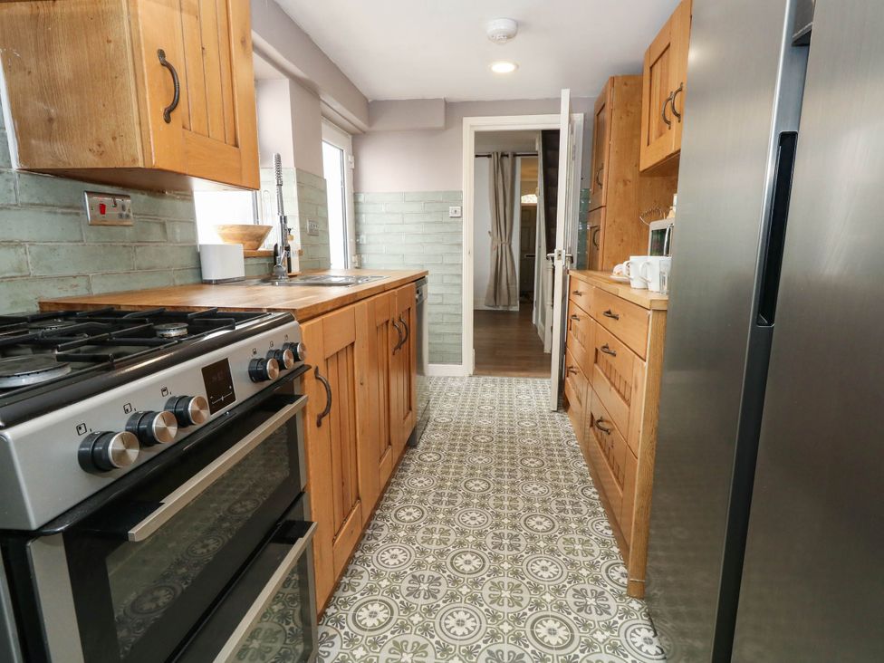 A kitchen with wooden cabinets and appliances at The Watch House in Weymouth