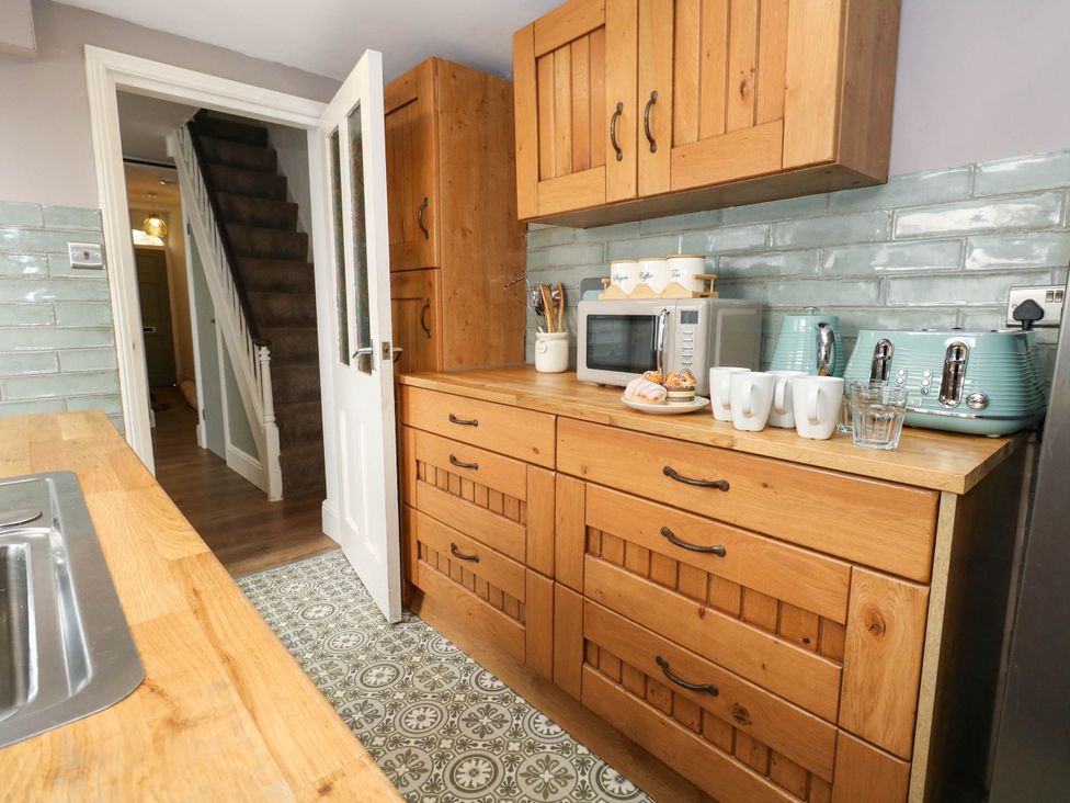 A kitchen with wooden cabinets and appliances at The Watch House in Weymouth