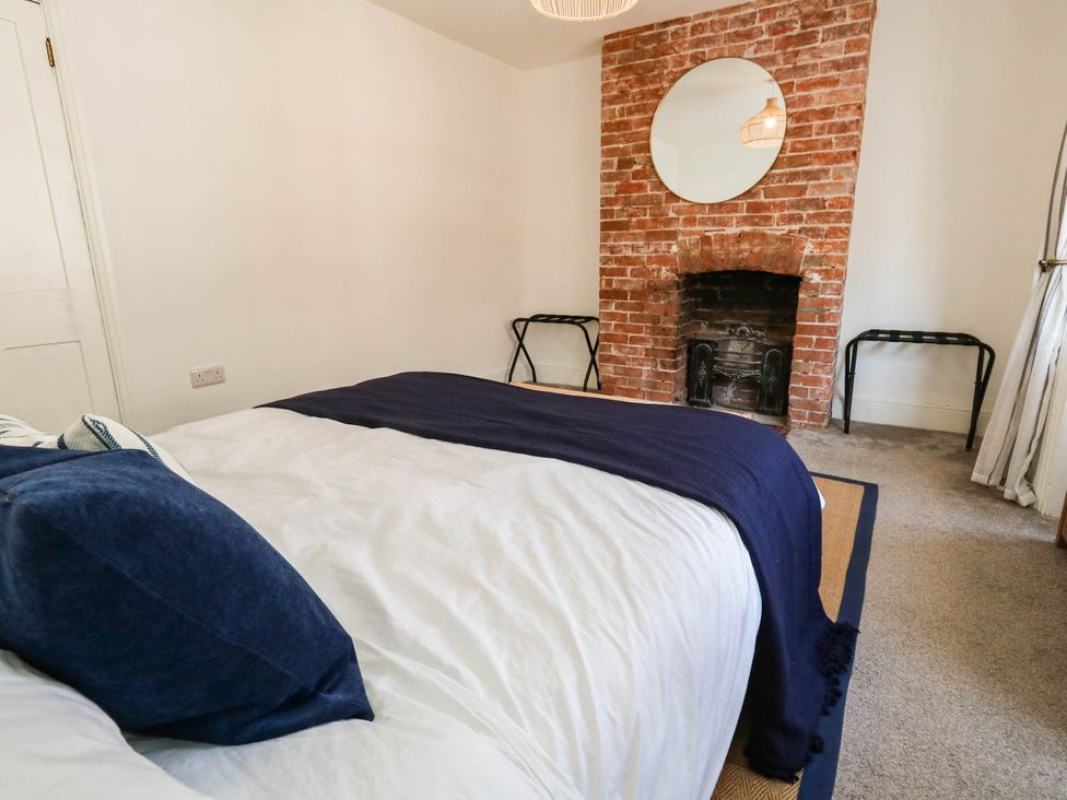 A bedroom with a bed and brick fireplace at The Watch House in Weymouth