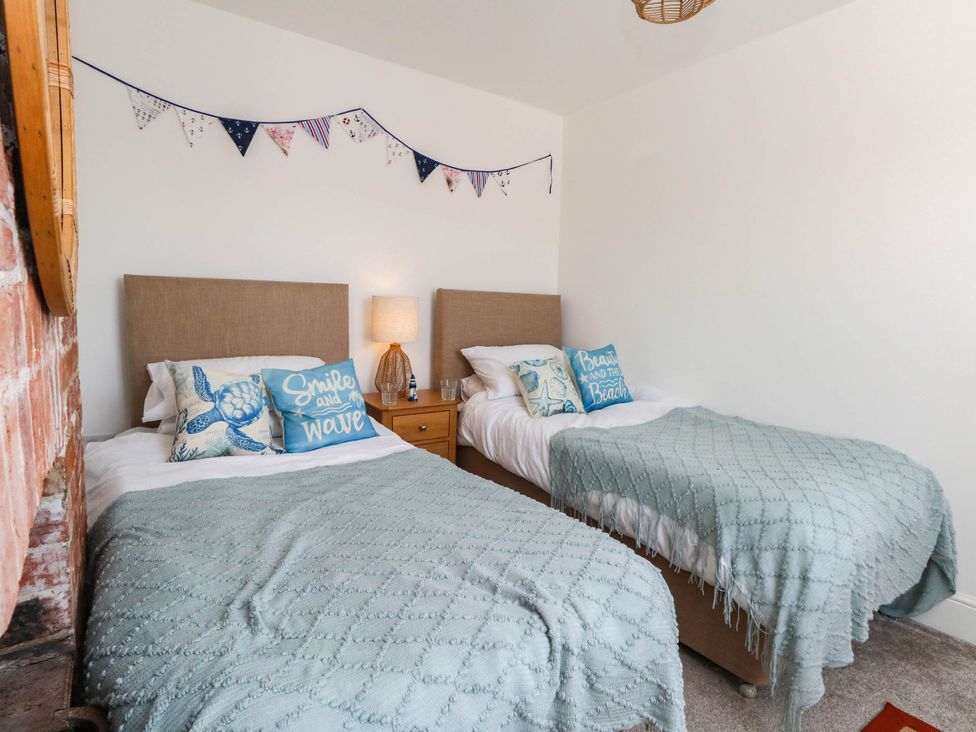 A bedroom with two beds, a lamp and bunting at The Watch House in Weymouth