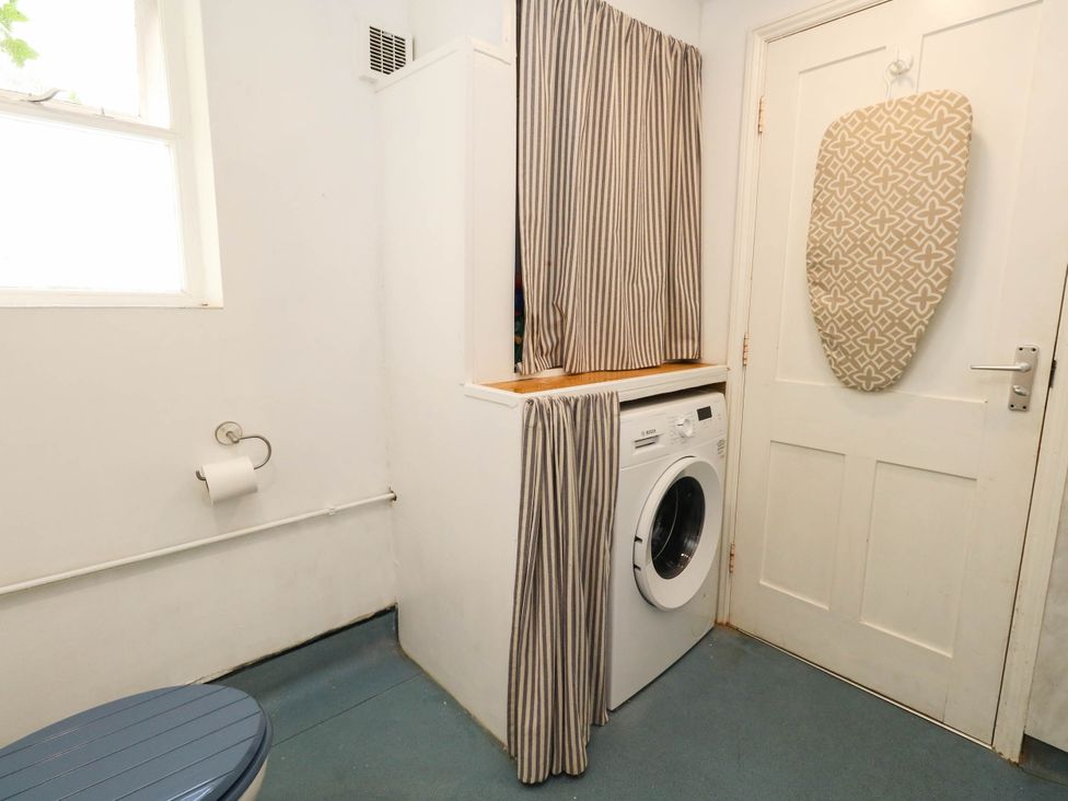 A laundry room with a toilet and washing machine at The Watch House in Weymouth