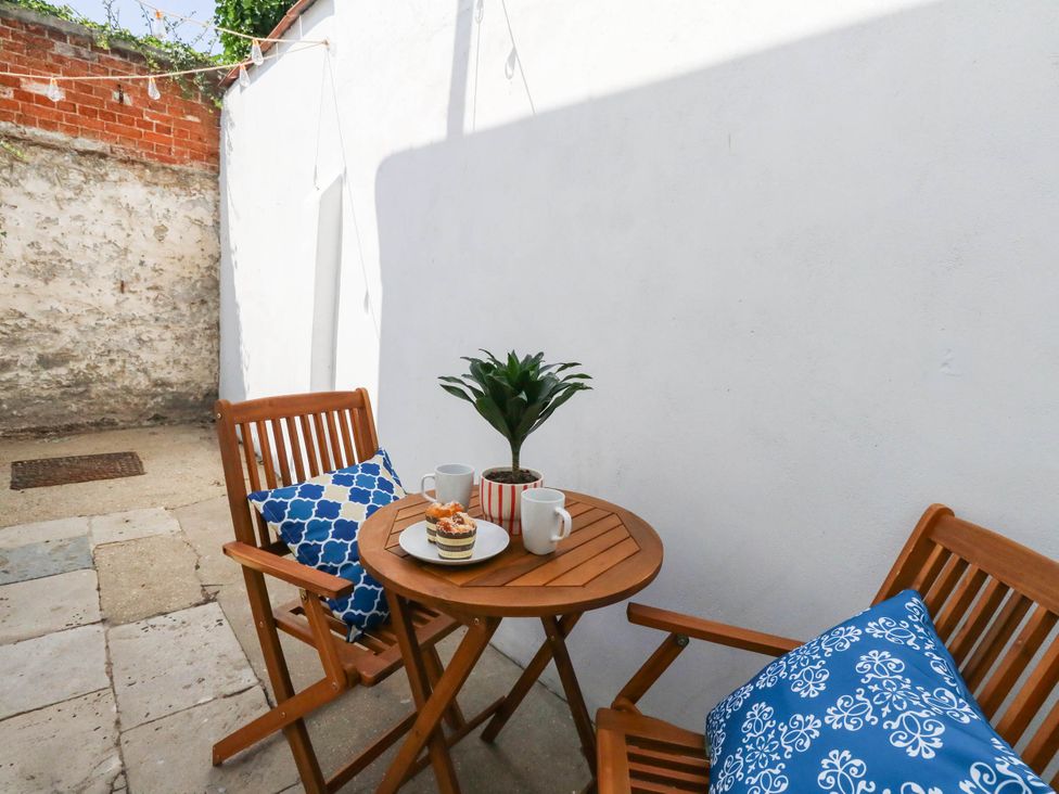 A table with mugs and a plant in a garden at The Watch House in Weymouth