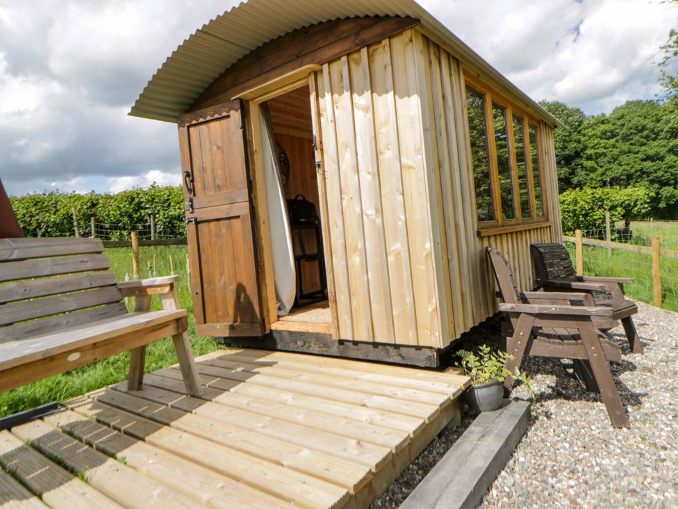 A wooden hut with a bench and chairs outside at The Little Shepherds Hut with a View Builth Wells