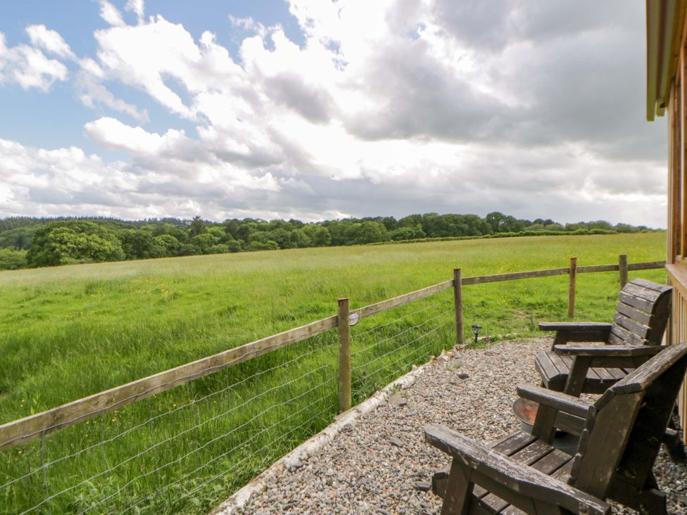 An outdoor area with wooden chairs overlooking a field at The Little Shepherds Hut with a View Builth Wells
