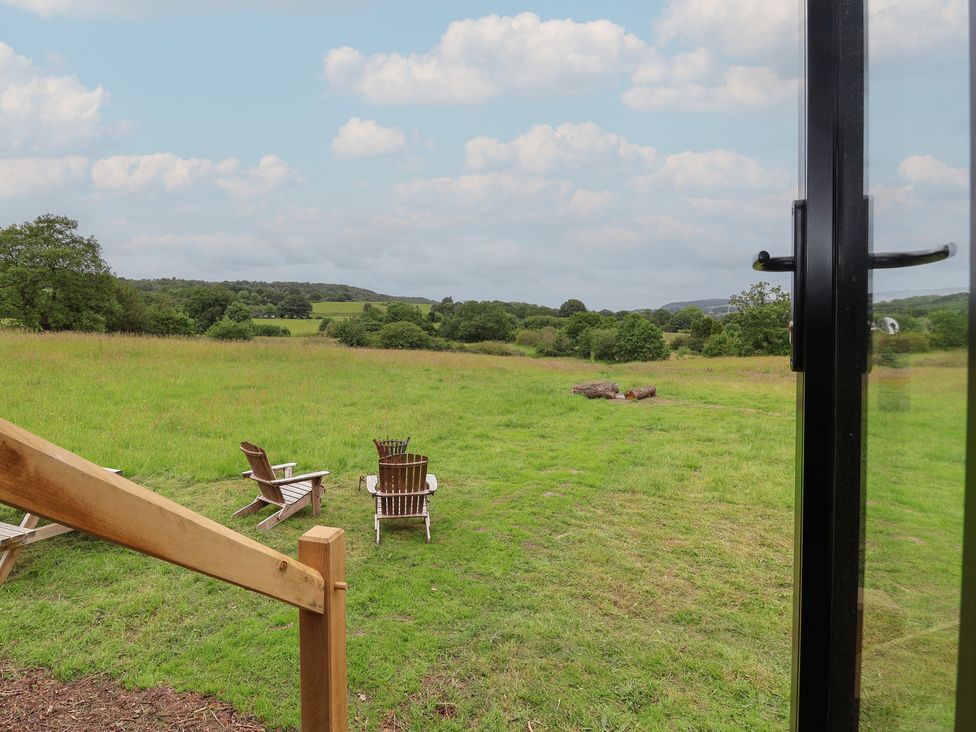 A field with wooden chairs and logs at Cloud Cabin