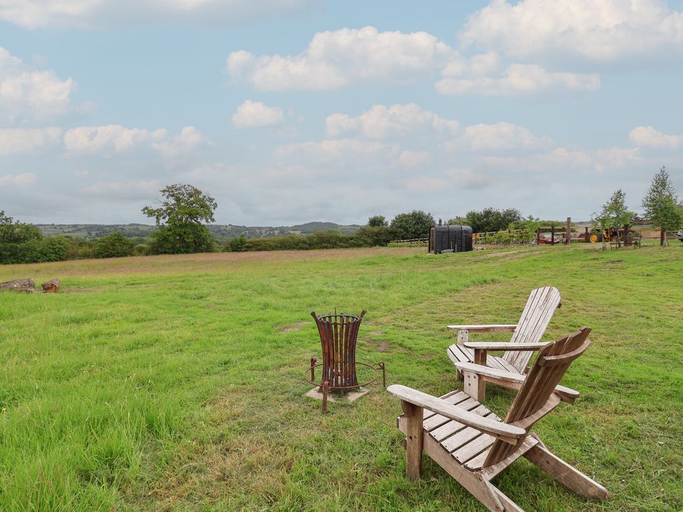 A view of wooden chairs and a fire pit on grass at Cloud Cabin