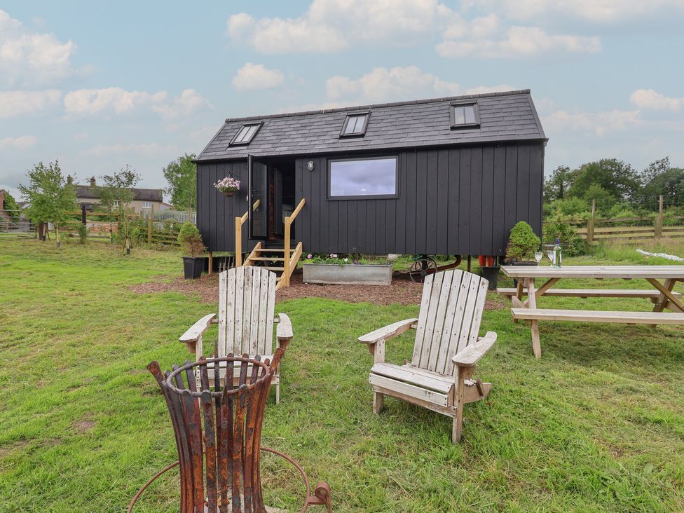 An outdoor area with a tiny house and wooden chairs at Cloud Cabin in 