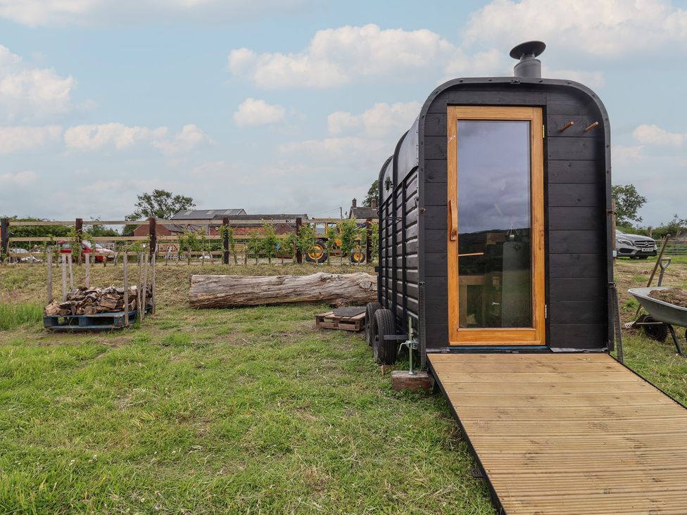 A black cabin with a wooden platform and firewood pile at Cloud Cabin in 