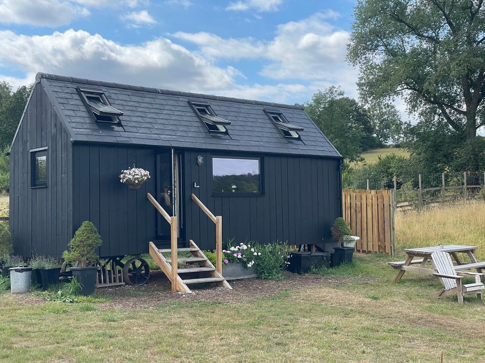 A black house with steps and plants outside at Cloud Cabin in Gillow Heath near Biddulph