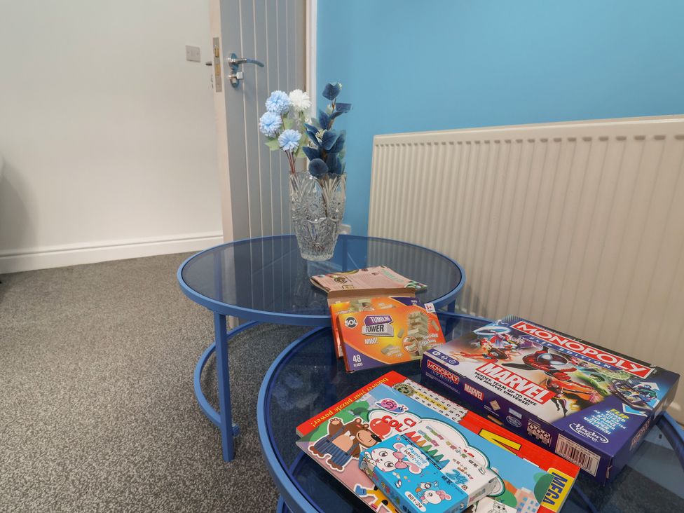 A living room with a blue table and board games at Lunt Road in Bootle