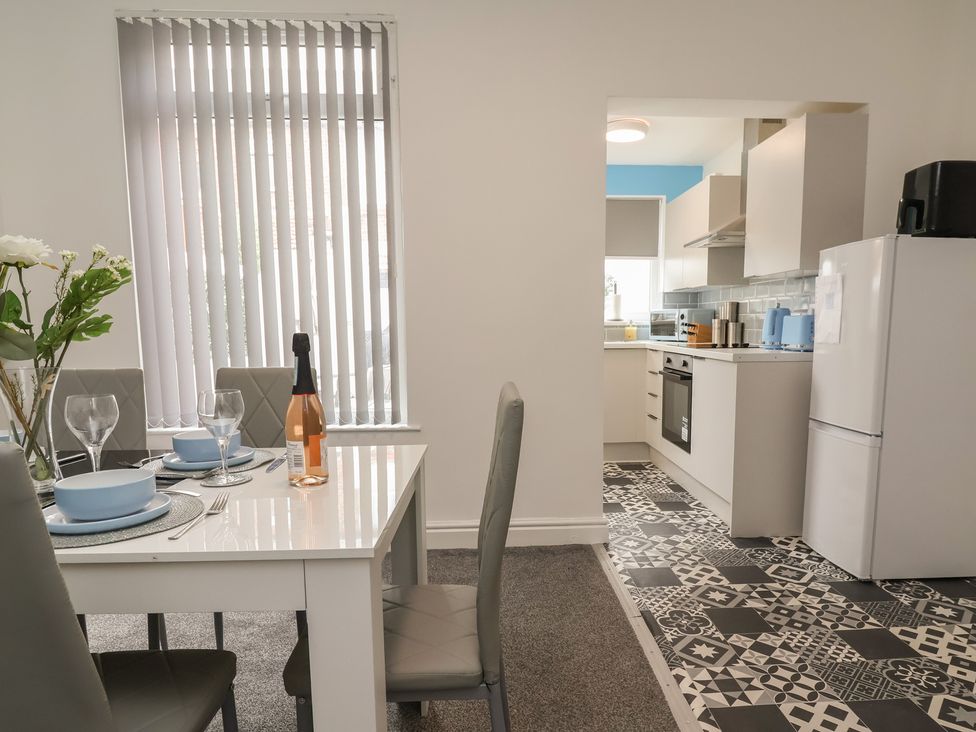 A dining room with a table and kitchen area at Lunt Road in Bootle
