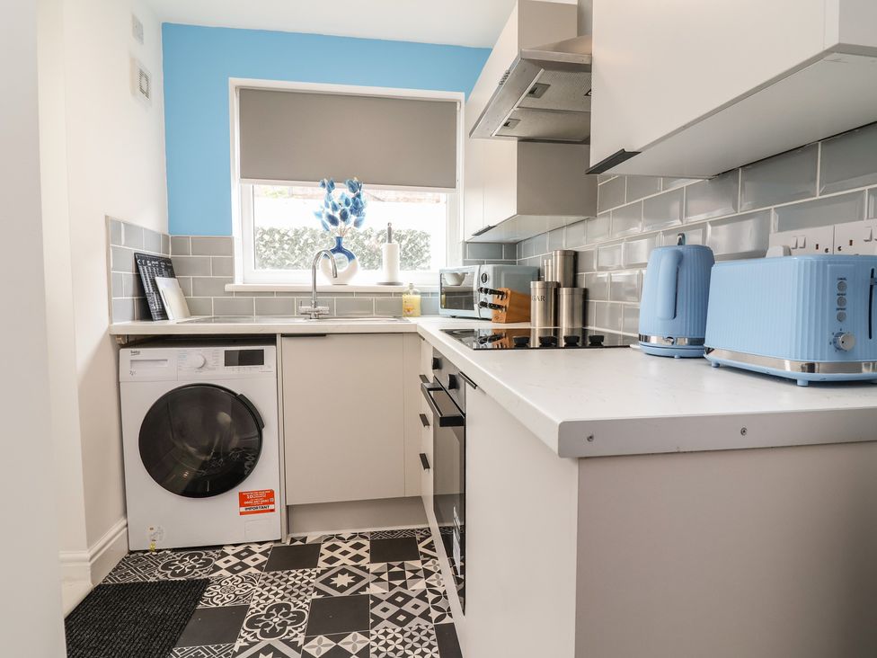 A kitchen with a washing machine, stove, and sink at Lunt Road in Bootle