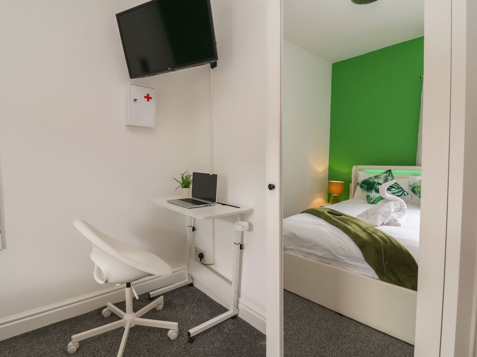 A bedroom with a desk and chair next to a bed at Lunt Road in Bootle