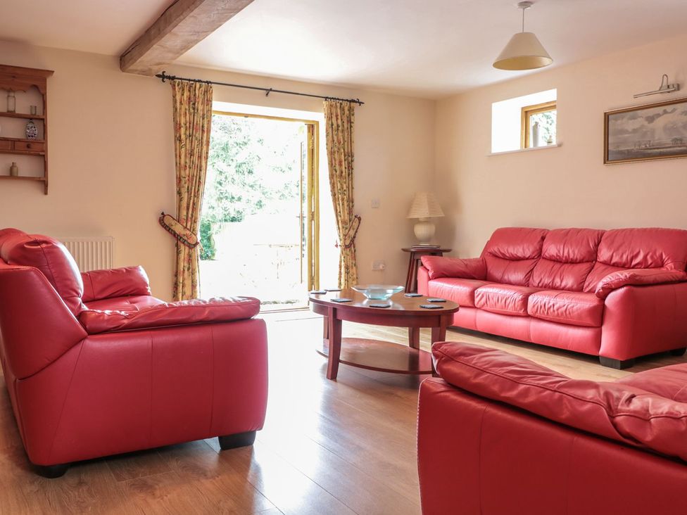A living room with red sofas and a round table at The Hop Kiln in Tenbury Wells