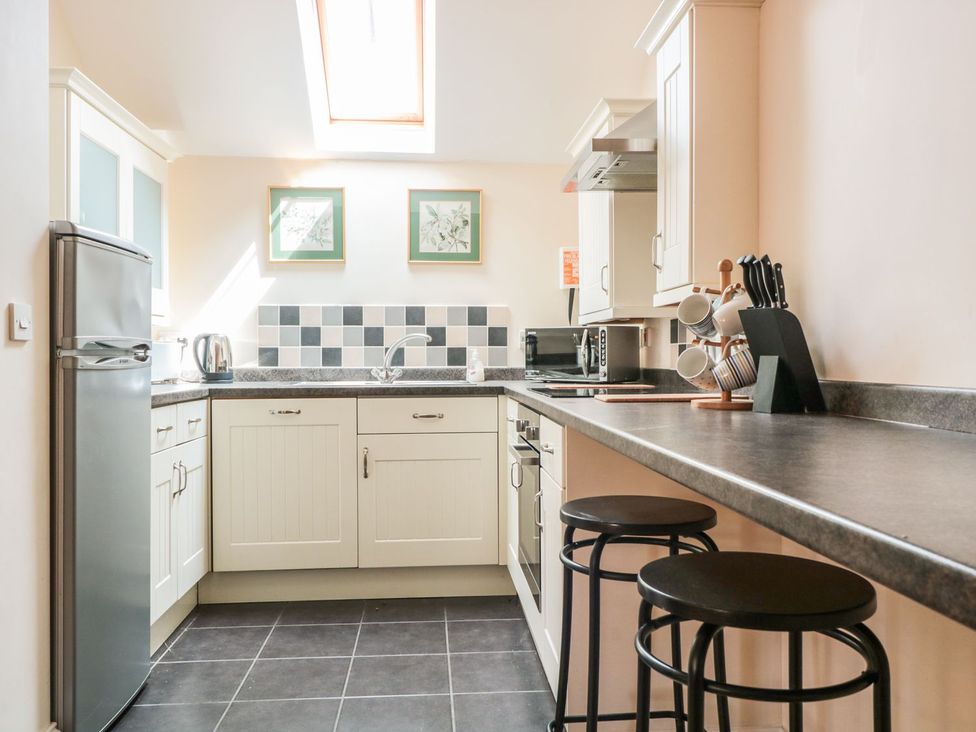 A kitchen with a refrigerator, sink, and stools at The Hop Kiln in Tenbury Wells