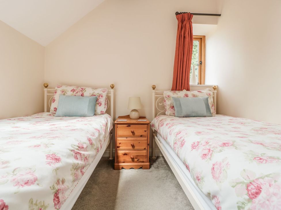 A bedroom with two beds and a nightstand at The Hop Kiln in Tenbury Wells