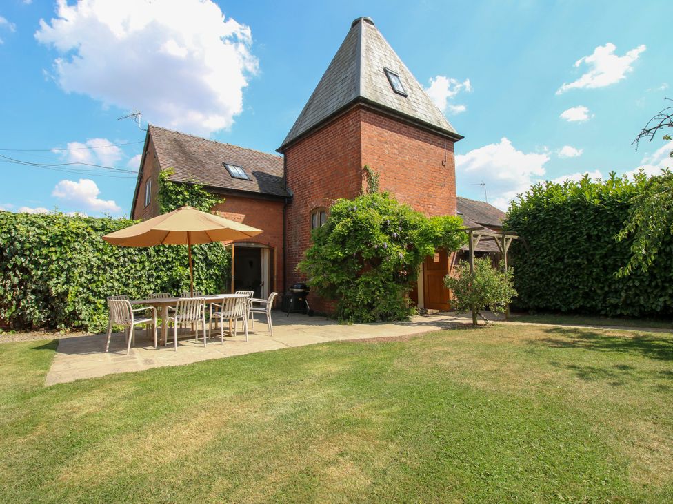 A garden with a table and chairs under a parasol at The Hop Kiln in Tenbury Wells