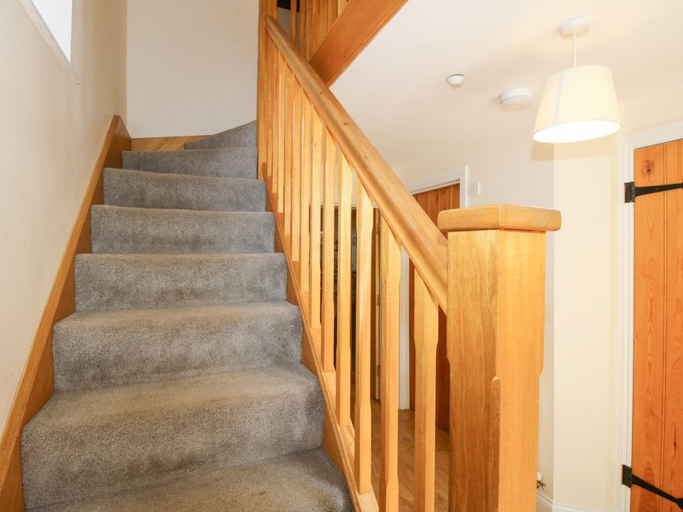 A stairway with wooden handrail and light fixture at The Hop Kiln in Tenbury Wells