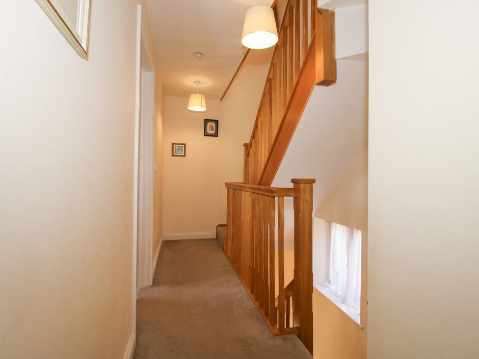 A hallway with a staircase and wall art at The Hop Kiln in Tenbury Wells