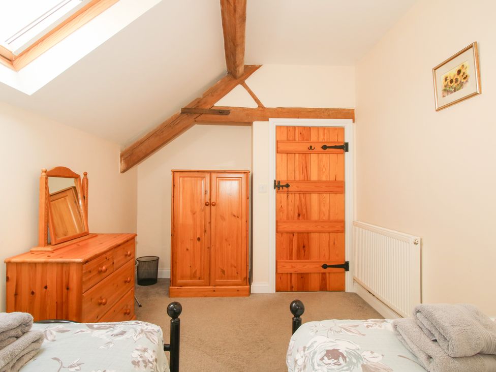 A bedroom with a bed, dresser, wardrobe, and door at The Hop Kiln in Tenbury Wells