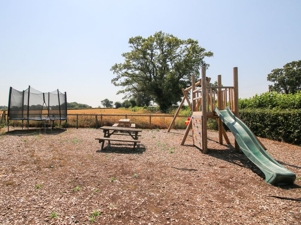 An outdoor play area with trampoline and playground at The Hop Kiln in Tenbury Wells