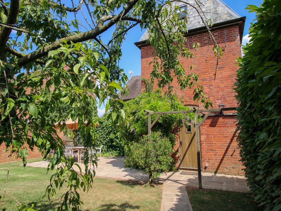 A garden with trees and a building at The Hop Kiln in Tenbury Wells