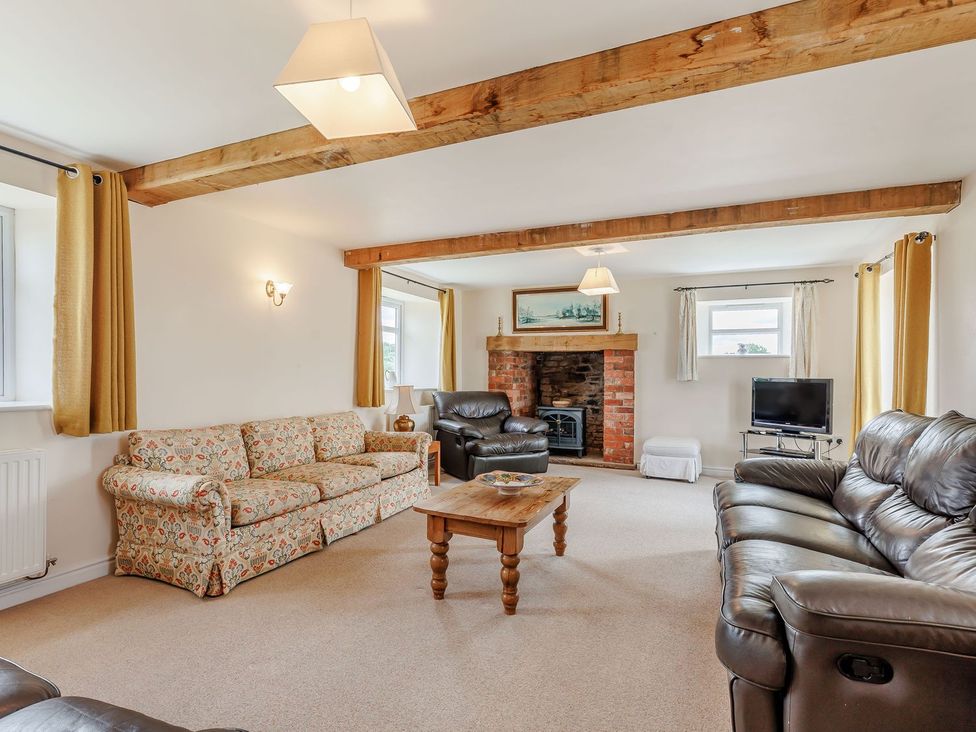 A living room with sofas and a fireplace at Wood Cottage in Tenbury Wells