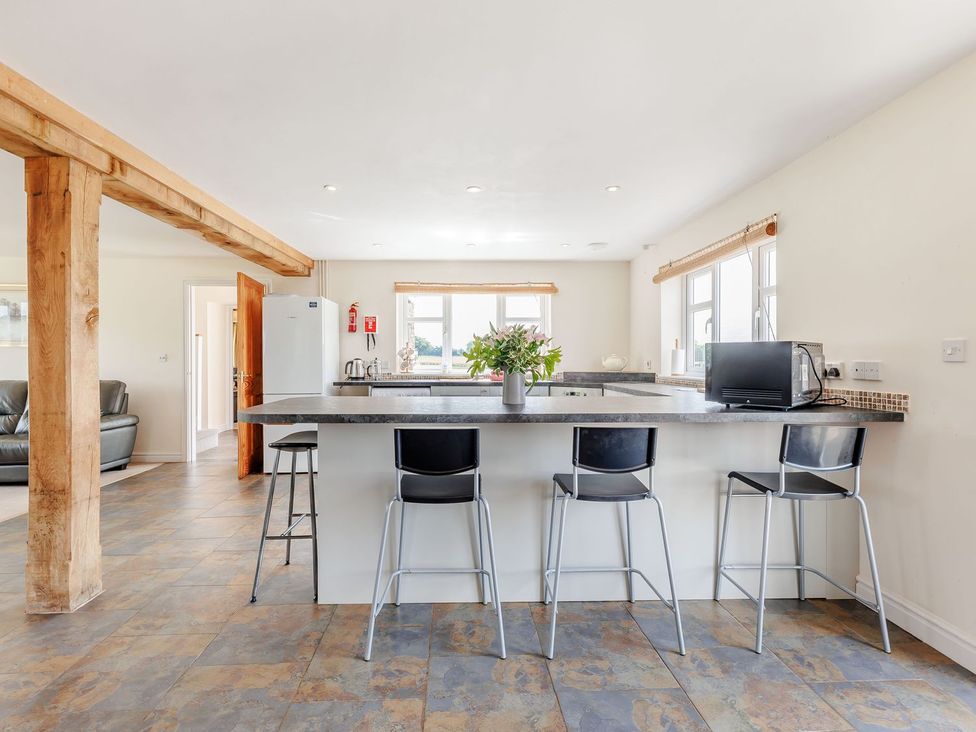 A kitchen with a counter and stools at Wood Cottage Tenbury Wells