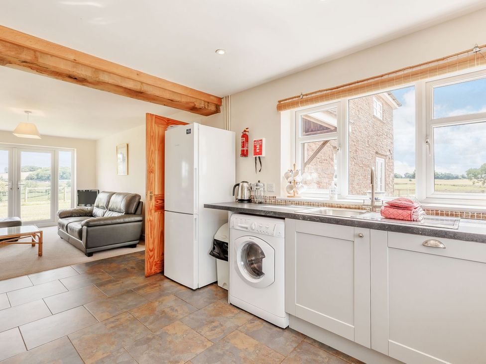 A kitchen with appliances and seating area at Wood Cottage in Tenbury Wells