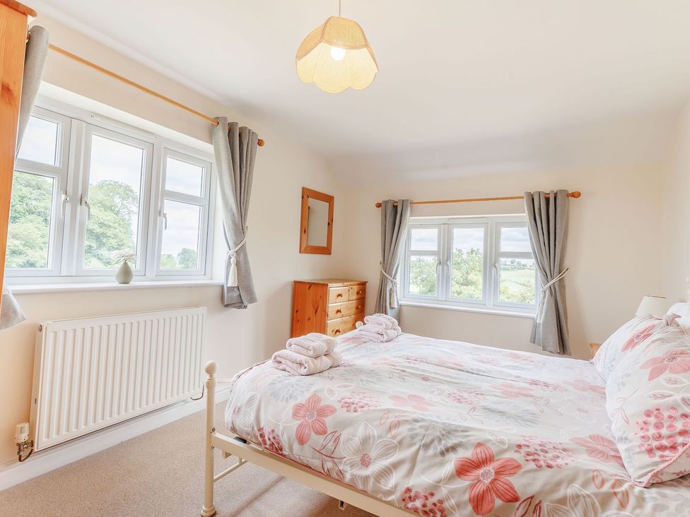 A bedroom with a bed and windows at Wood Cottage in Tenbury Wells