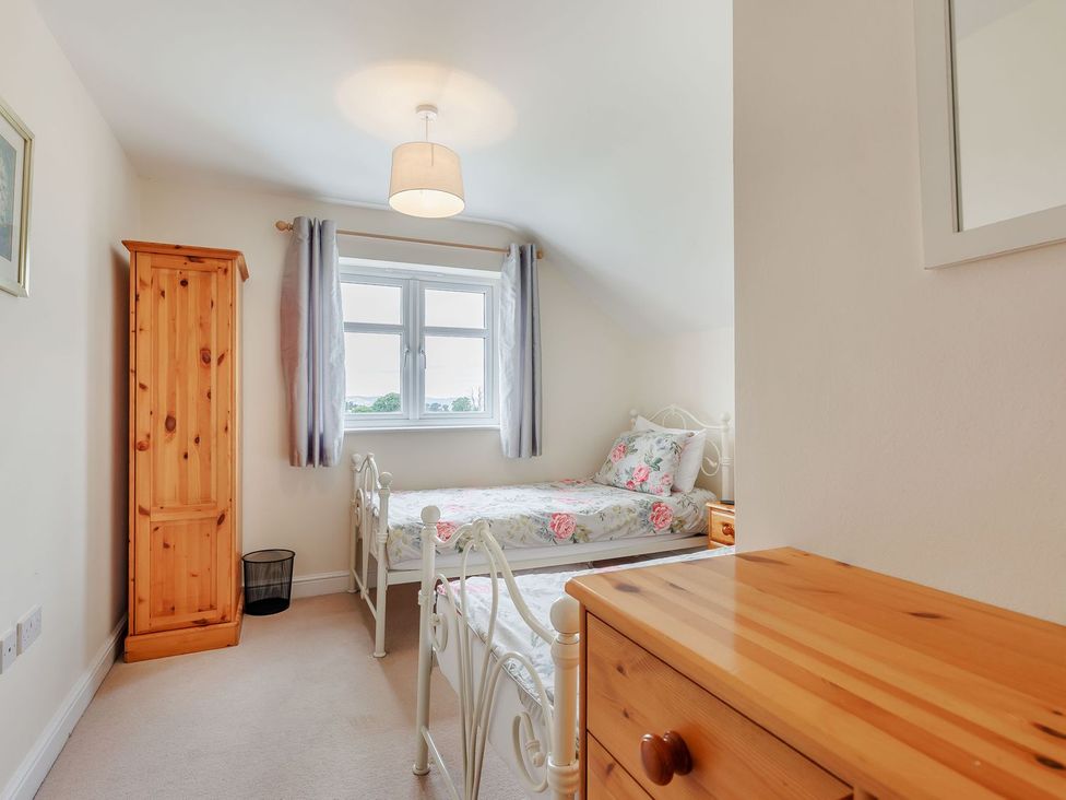 A bedroom with two beds and a wardrobe at Wood Cottage in Tenbury Wells