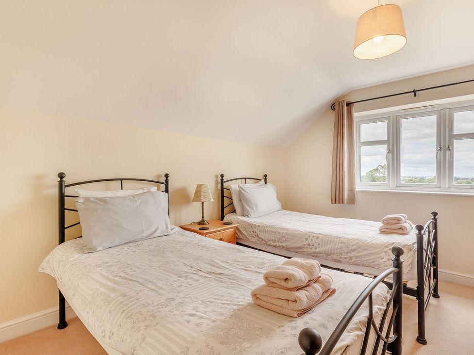 A bedroom with two beds and a bedside table at Wood Cottage in Tenbury Wells
