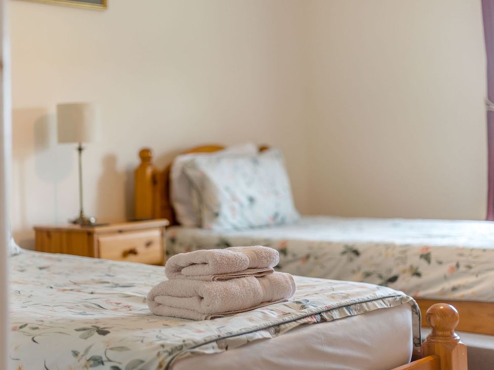 A bedroom with two beds and towels on one at Wood Cottage in Tenbury Wells