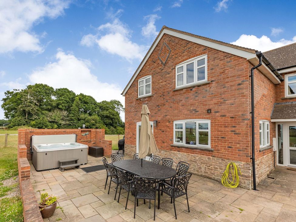 An outdoor patio with a hot tub and dining set at Wood Cottage in Tenbury Wells