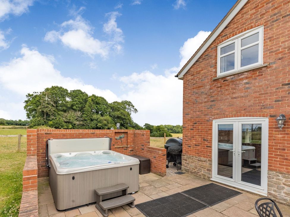 An outdoor area with a hot tub and grill at Wood Cottage in Tenbury Wells