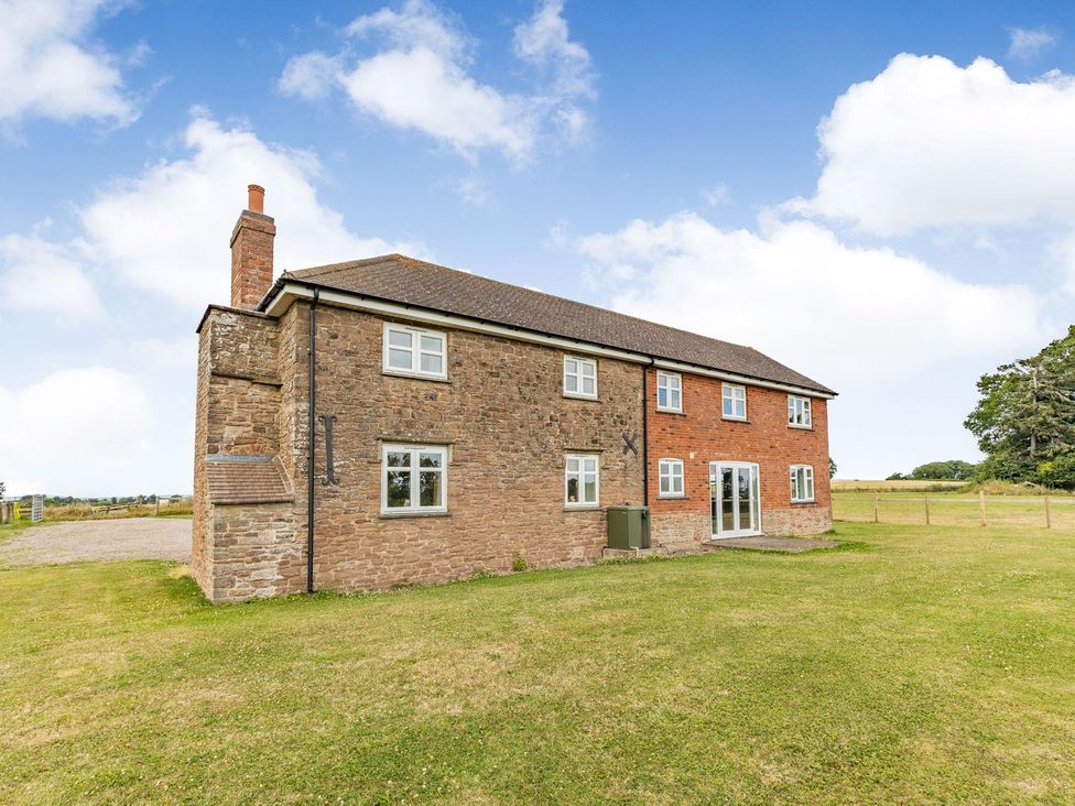 A house with windows and a door surrounded by grass at Wood Cottage, Tenbury Wells
