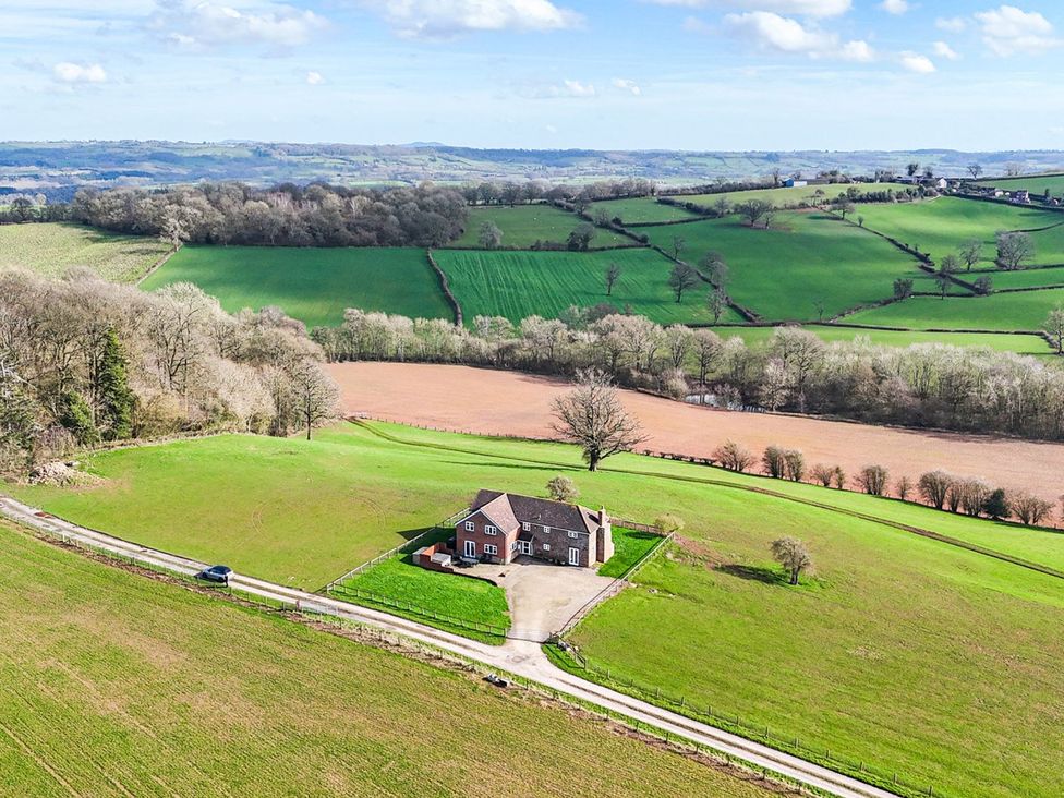 A house surrounded by fields and trees at Wood Cottage in Tenbury Wells