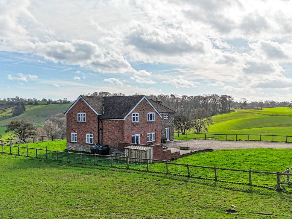 A house with a grassy field and fence at Wood Cottage in Tenbury Wells
