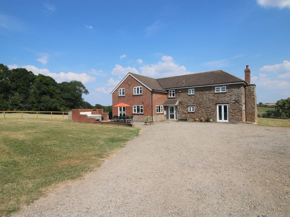 A house with a patio and chairs at Wood Cottage in Tenbury Wells