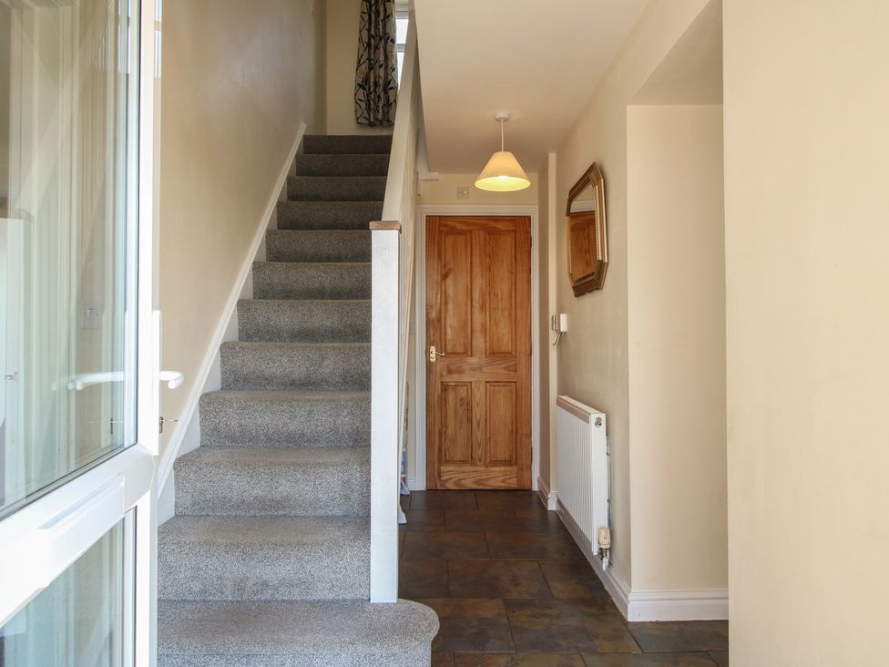 A hallway with stairs and a door at Wood Cottage in Tenbury Wells