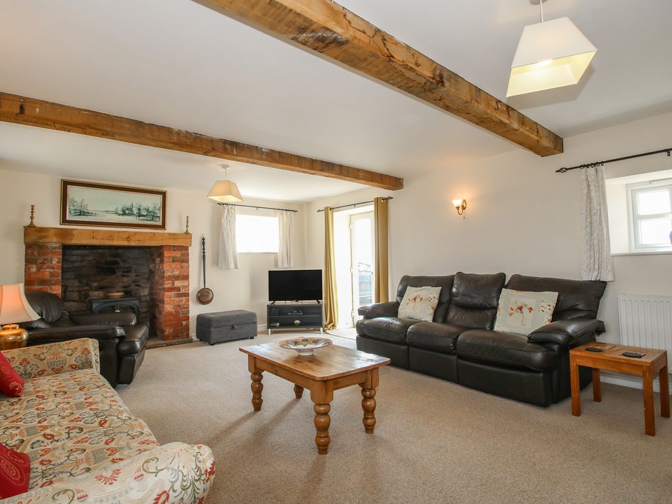 A living room with a fireplace and sofa at Wood Cottage in Tenbury Wells