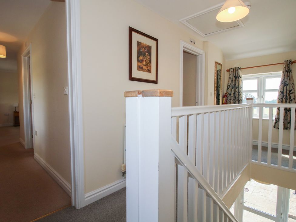 A hallway with a stair railing and doors at Wood Cottage Tenbury Wells