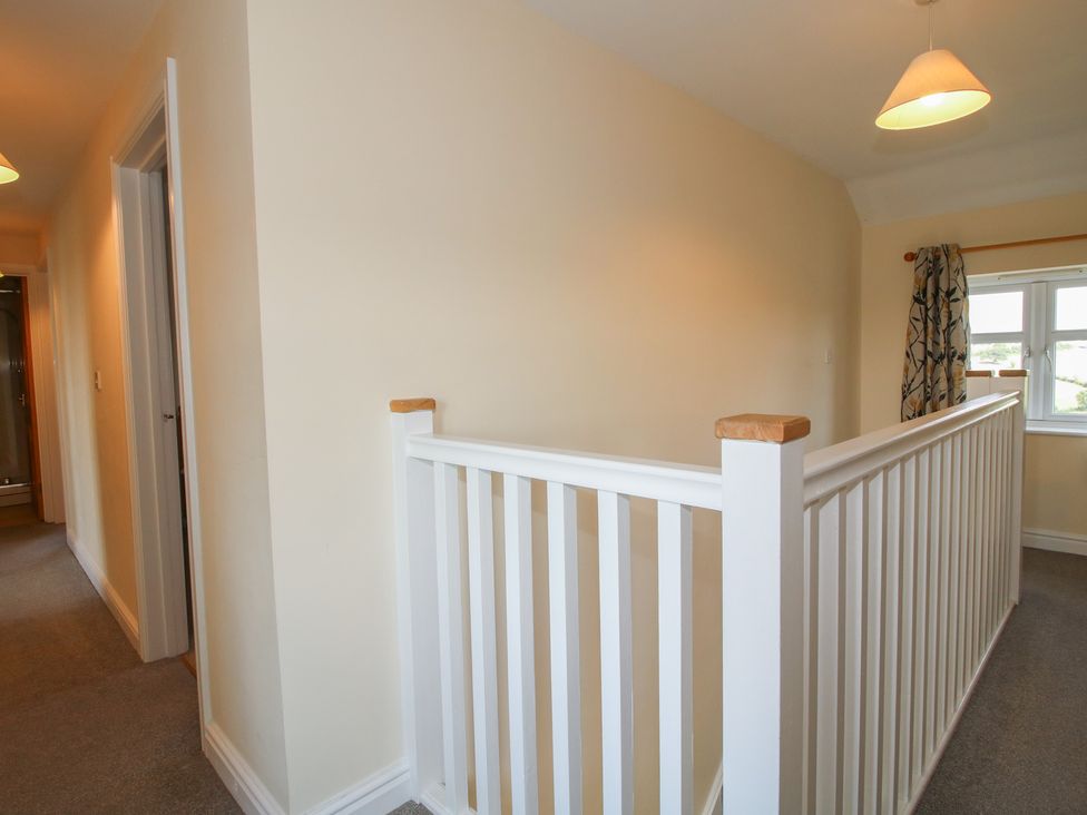 A hallway with a balustrade and a door at Wood Cottage in Tenbury Wells